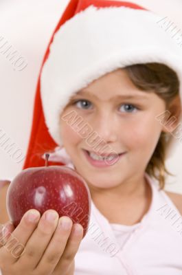 girl wearing christmas hat and holding an apple