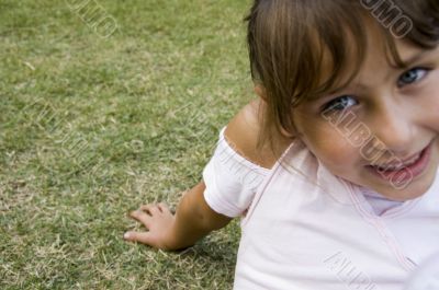 smiling little girl sitting on grass