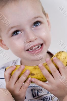 little boy smiling and holding a banana