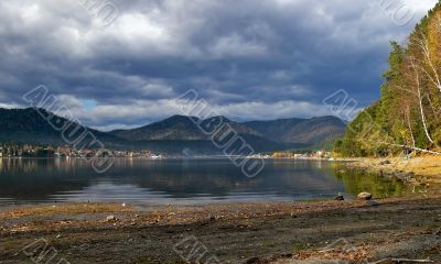 Coastline lake Teletskoe and cloudscape.