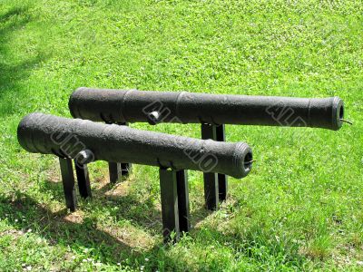 Two ancient rusty cannons on a green grass background