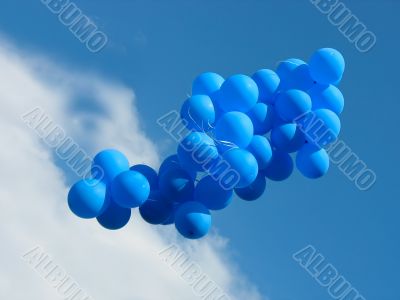 Sheaf of blue party balloons against the cloudy blue sky