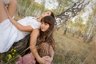 two girls sit near birch