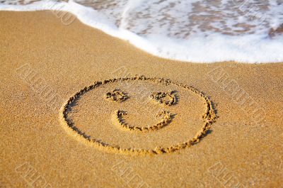`Smile` drawing at sand, with sea wave