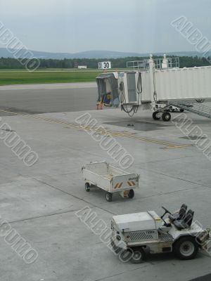 empty airplane gate with small trucks