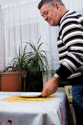 Gradfather is setting the table for breakfast