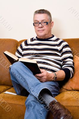 Senior reading his book on the couch