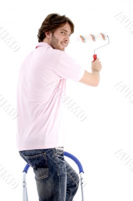 man standing on chair and holding paint roller