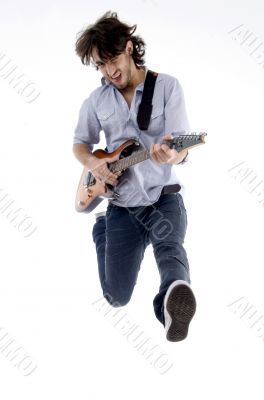 young male jumping high holding his guitar