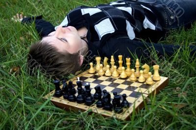 Woman lying in the grass near the chess board
