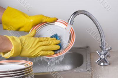 Man hands in, washing the dishes at the kitchen