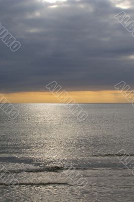 Yellow sunset over the sea with dark clouds
