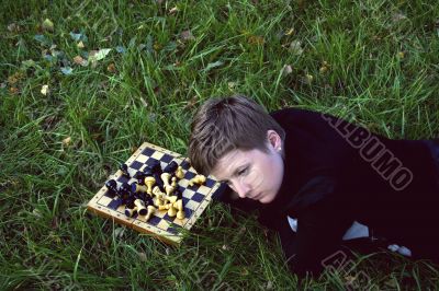 Woman lying in the grass near the chess board