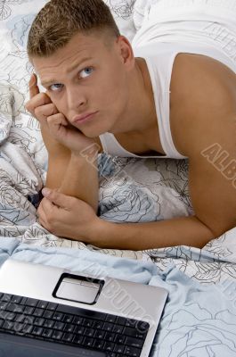 young guy thinking with laptop