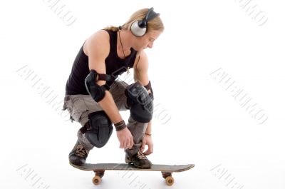 guy tying his shoes laces sitting on skateboard