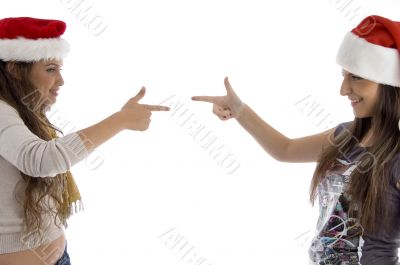 siblings in christmas hat pointing at each other