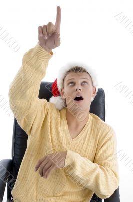 man wearing christmas hat pointing upward