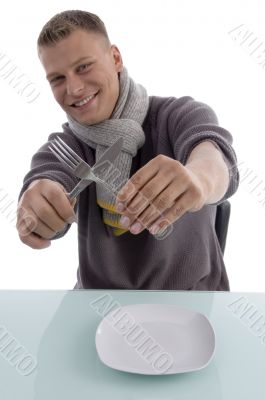 smiling young man holding fork and knife