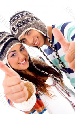 cute couple wearing warm cap showing thumbs up
