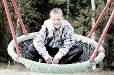 Happy blond boy in the swing