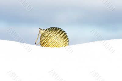 golden christmas bauble in snow