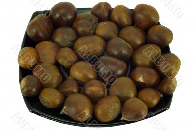 Chestnuts on dark plate isolated on white background