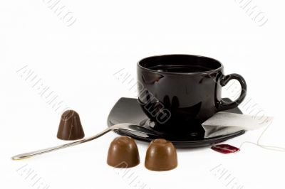 Tea cup, teaspoon and chocolates isolated