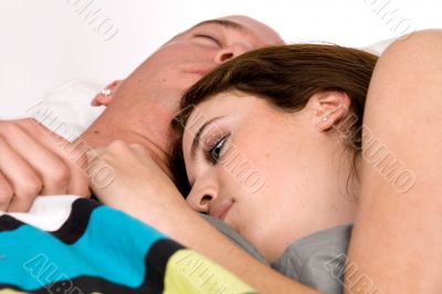 Young couple in bed slowly waking up