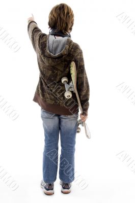back pose of pointing boy holding skateboard