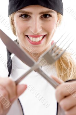 front view of cheerful cook holding fork and knife