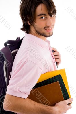 smiling college boy posing with his bag and books