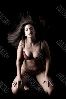 Lingery dressed brunette in a low key setting waving her hair