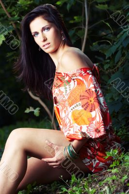 beautiful girl sitting on grass in beautiful and colourful dress