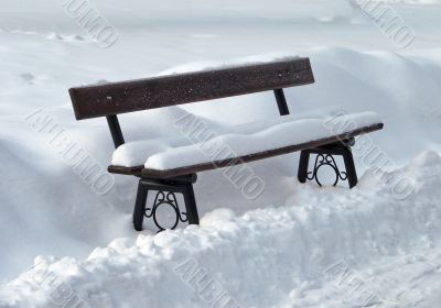 Snowed antique wooden park bench