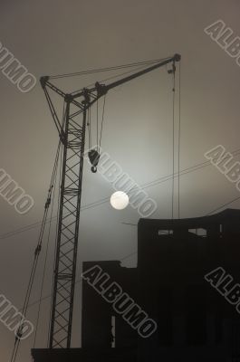 Gray sunset sky with lifting construction cranes
