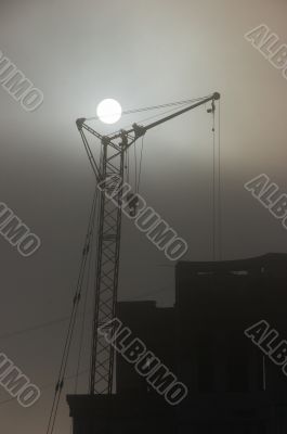 Gray sunset sky with lifting construction cranes