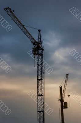 Sunset cloudy sky with lifting cranes