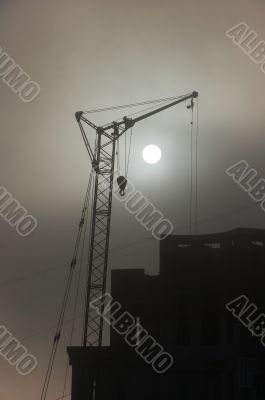 Gray sunset sky with lifting construction cranes