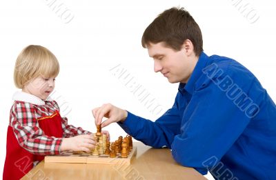 Man and child play chess