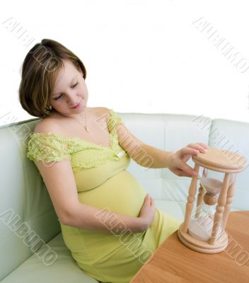 Pregnant woman looking on the hourglass