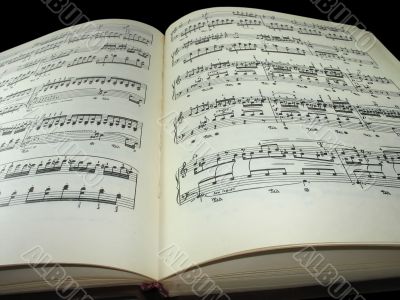 old vintage sheet music book over black background