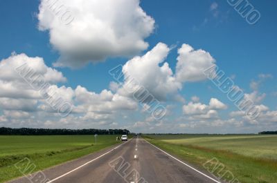 countryside asphalt road under cloudy blue sky