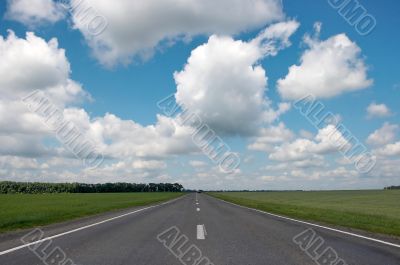 countryside asphalt road under cloudy blue sky