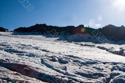 The picturesque mountain view with snow, sky and patch of sunlig