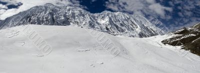 The picturesque mountain view with clouds, stones, peak and snow