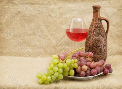 Ceramic brown bottle, grapes and goblet