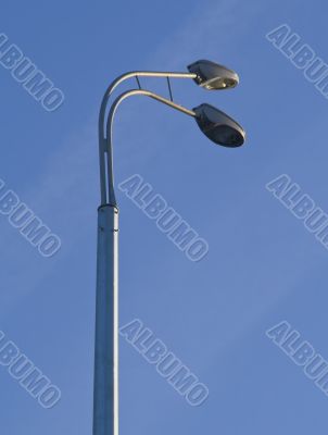 two grey street lamppost in blue sky