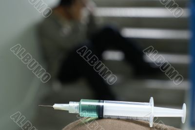 Sad addict and syringe in foreground