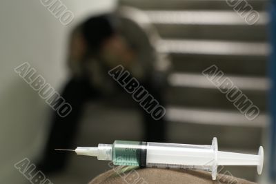 Sad addict and syringe in foreground