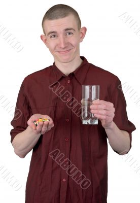 Young man with glass of water and tablets
